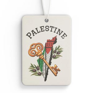 May include: A rectangular air freshener with the word "PALESTINE" above a map outline and a key. The map is colored with the Palestinian flag and olive branches. The key is gold-colored, and a white string is attached.
