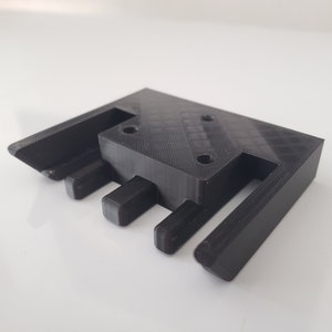 May include: Black plastic 3D printed part with three slots and four holes.