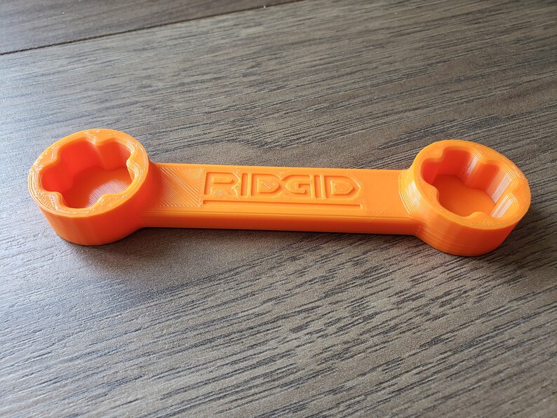 May include: An orange wrench with two 6-point sockets on either end. The wrench is labeled "RIDGID" in the center.