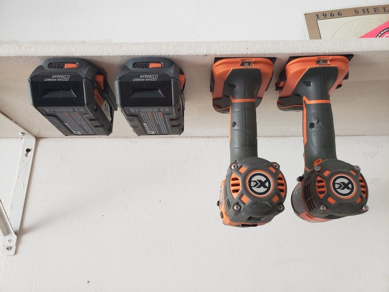 May include: Four black and orange power tool batteries and two black and orange power tools hanging on a white shelf. The batteries are labeled "HYPER" and "Lithium Ion 20V".