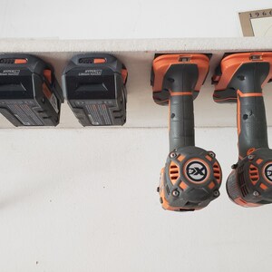 May include: Four black and orange power tool batteries and two black and orange power tools hanging on a white shelf. The batteries are labeled "HYPER" and "Lithium Ion 20V".
