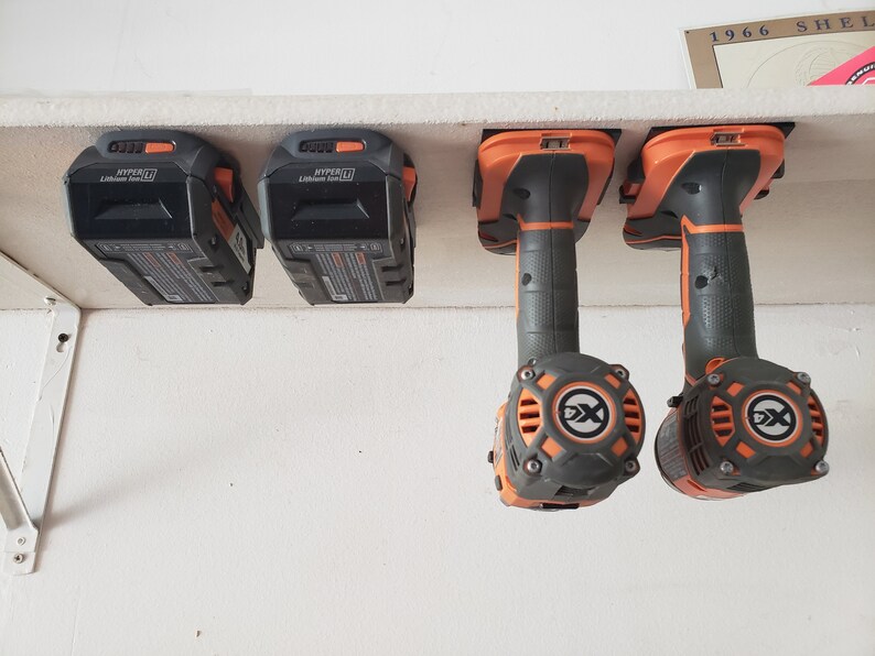 May include: Four black and orange power tool batteries and two black and orange power tools hanging on a white shelf. The batteries are labeled "HYPER" and "Lithium Ion 20V".
