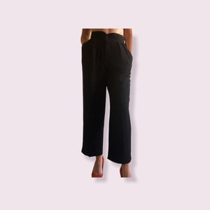 May include: Black high-waisted pants with a wide leg and a center front button closure.