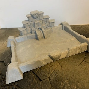 May include: A gray 3D printed miniature of a stone temple ruin with a square base and a small water feature. The temple is made of stacked blocks with intricate details and a small archway. The base is textured to resemble stone.