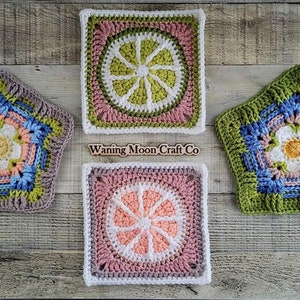 May include: Four crocheted squares and a star, each featuring a different floral design. The squares are in shades of pink, white, and green, while the star is in shades of gray, blue, and green. The squares and star are arranged on a wooden surface. The text "Waning Moon Craft Co" is visible in the image.