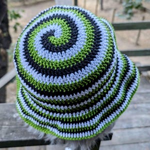 May include: A green, black, and white crocheted bucket hat with a spiral pattern.