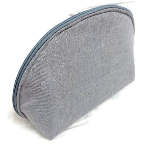 May include: A gray zippered pouch made of a textured fabric. The pouch is shaped like a half-circle.