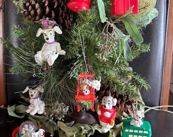 Peut inclure: Une collection de décorations de Noël Disney 101 Dalmatiens représentant divers personnages dans des scènes incluant une chaussette rouge, un cadeau rouge, une chaise à bascule avec le texte Happy Holidays, un traîneau rouge et un bus vert.