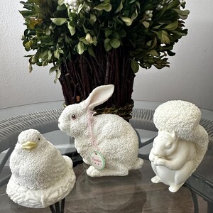 May include: Three white ceramic figurines of a rabbit, a bird, and a squirrel. The rabbit is holding a tag that says "Easter 1997".