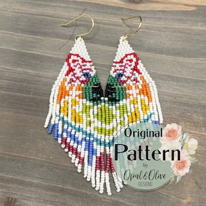 May include: A pair of rainbow beaded earrings with a fox face design. The earrings are made with white seed beads and feature a variety of colors, including red, orange, yellow, green, blue, and purple. The earrings are labeled "Original Pattern by Opal & Olive Designs."