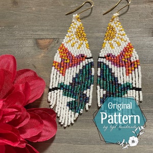 May include: A pair of white beaded earrings with a geometric pattern in shades of orange, pink, teal, and gold. The earrings are hanging from gold hooks.