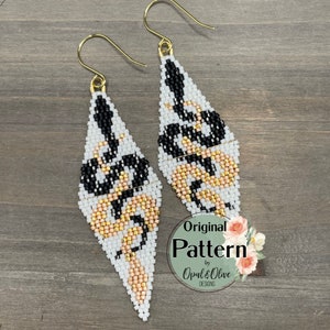 Puede incluir: Un par de pendientes de cuentas blancas, negras y doradas con un diseño geométrico. Los pendientes tienen forma de lágrima y tienen ganchos dorados. Los pendientes están etiquetados como "Original Pattern by Opal & Olive Designs".