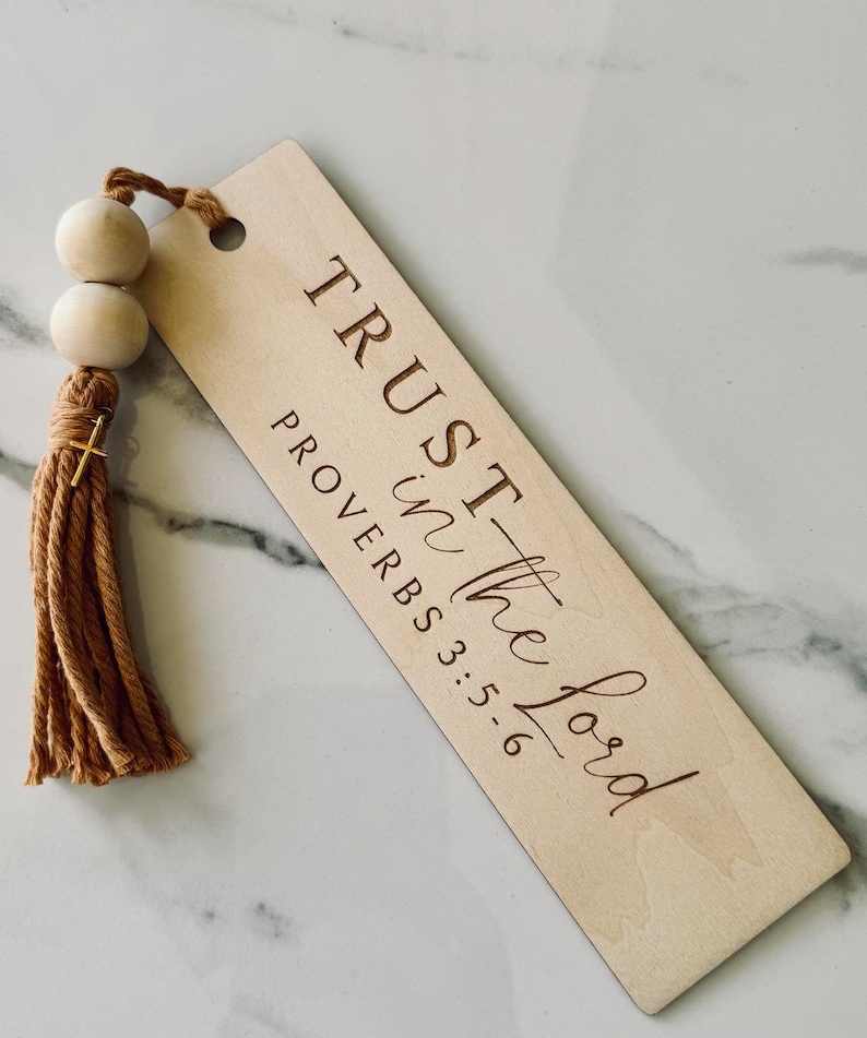 May include: Wooden bookmark with a brown tassel and wooden beads. The bookmark has the text "TRUST in the Lord" and "PROVERBS 3:5-6" engraved on it.