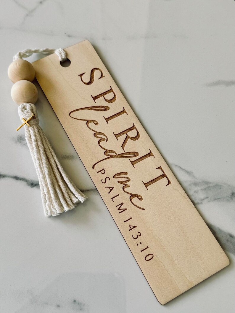 May include: Wooden bookmark with a white tassel and wooden beads. The bookmark is engraved with the text "SPIRIT lead me PSALM 143:10".