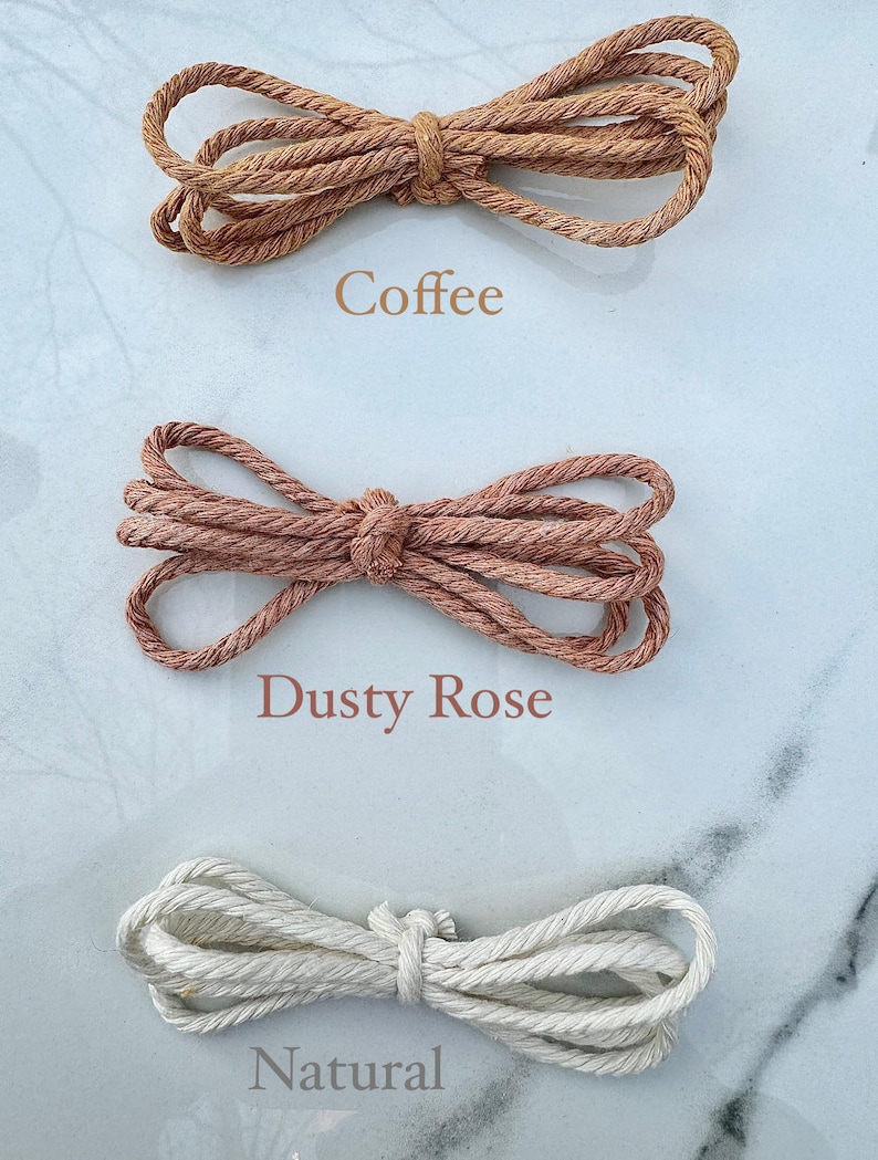 May include: Three spools of natural fiber rope in different colors: coffee, dusty rose, and natural. The rope is twisted and has a rough texture.