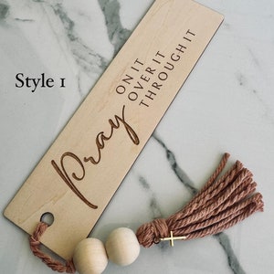 May include: Wooden bookmark with the words "Pray On It Over It Through It" and a tassel with wooden beads.