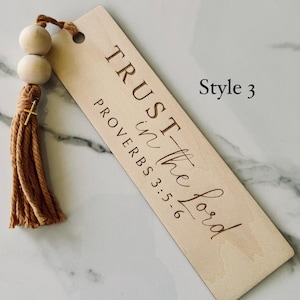 May include: A wooden bookmark with a brown tassel. The bookmark has the text "TRUST in the Lord" and "PROVERBS 3:5-6" engraved on it. The bookmark is labeled "Style 3".