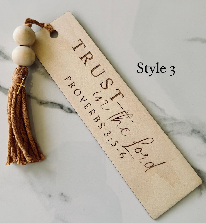May include: A wooden bookmark with a brown tassel. The bookmark has the text "TRUST in the Lord" and "PROVERBS 3:5-6" engraved on it. The bookmark is labeled "Style 3".