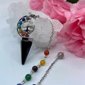 May include: Black crystal pendulum with a silver tree of life charm and rainbow coloured beads. The pendulum is attached to a silver chain with a small silver ball at the end.