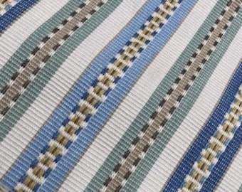 May include: Close-up of a fabric with a striped pattern. The design features alternating vertical stripes in white, blue, and green, with a textured weave. The stripes are accented with a dotted pattern in brown and gray.
