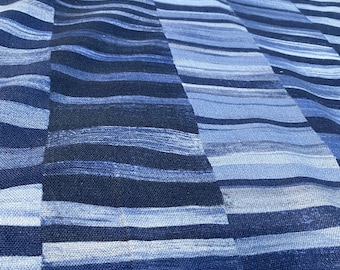 May include: Close-up of a blue fabric with a striped pattern. The design features horizontal stripes in varying shades of blue, creating a textured, wave-like effect. The fabric appears to be a medium weight, suitable for various textile projects.
