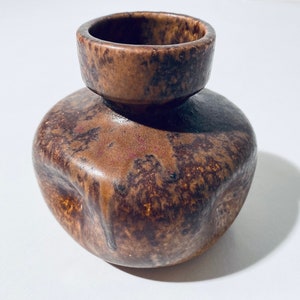 Może przedstawiać: Mały, brązowy wazon ceramiczny z fakturowaną, marmurkową glazurą. Wazon ma zaokrąglone ciało i szeroki, otwarty otwór.
