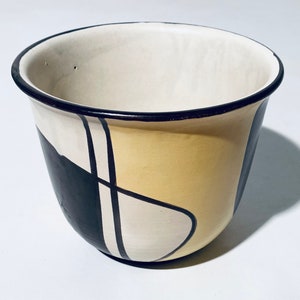 May include: A ceramic bowl with a black, white and yellow geometric design.