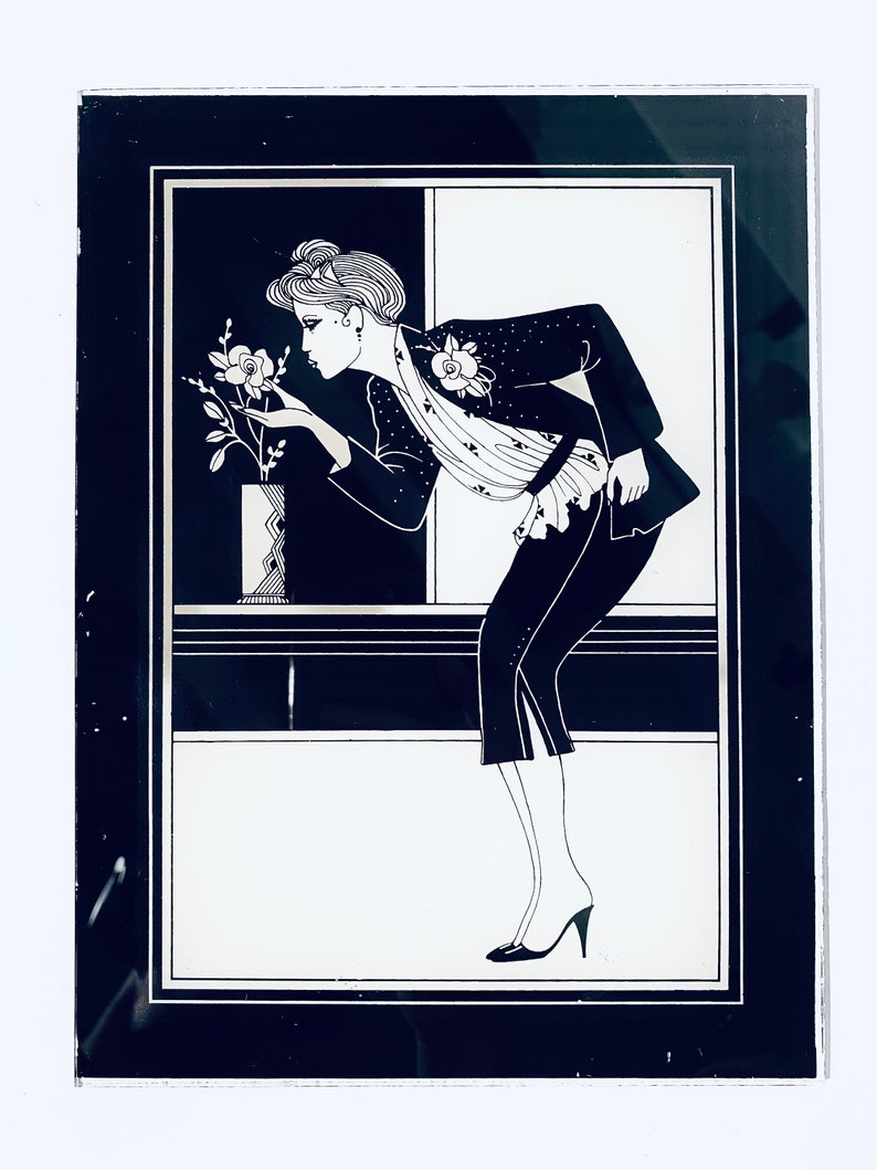 May include: A black and white illustration of a woman in a black jacket and skirt, smelling a flower in a vase. The image is framed in a black frame.