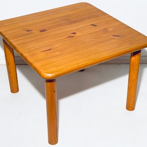 Könnte beinhalten: Ein quadratischer Holz-Couchtisch mit hellbrauner Oberfläche und vier stabilen Beinen.
