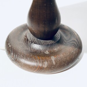 May include: A dark brown wooden table lamp base with a rounded, bulbous shape. The base has a smooth, polished finish and a slightly textured surface.