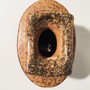 Może przedstawiać: Brązowy i czarny ceramiczny wazon z kwadratowym otworem. Wazon ma pstrokatą glazurę.