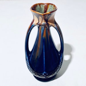 Peut inclure: Un vase en céramique bleu et brun avec deux anses. Le vase a un motif en spirale unique et une base texturée.