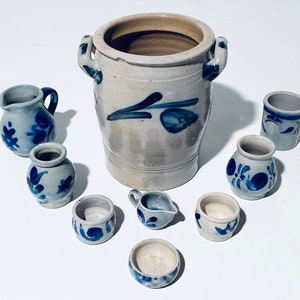 Könnte beinhalten: Ein Set aus acht blauen und weißen Keramikstücken, darunter ein großes Krug mit Blumenmuster, ein Krug und sechs kleine Tassen. Alle Stücke sind handbemalt mit blauen Blumenmustern auf weißem Hintergrund.