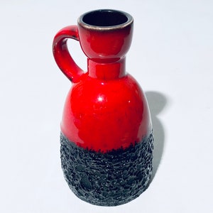 Könnte beinhalten: Eine rote und schwarze Keramikvase mit einem strukturierten Boden und einem Henkel. Die Vase ist etwa 25 cm hoch.
