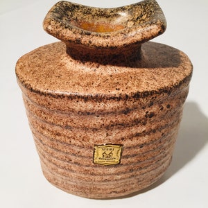 Może przedstawiać: Brązowy ceramiczny wazon z fakturowaną powierzchnią i złotą etykietą z napisem "Vest, Handgefertigt, West Germany".