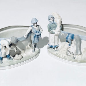 Könnte beinhalten: Zwei Porzellan-Pflanzschalen mit Relief-Figuren, die eine Ernteszene darstellen. Die Schalen sind weiß mit blauen Akzenten und zeigen Figuren in traditioneller Kleidung. Eine Figur trägt ein Weizenbündel.