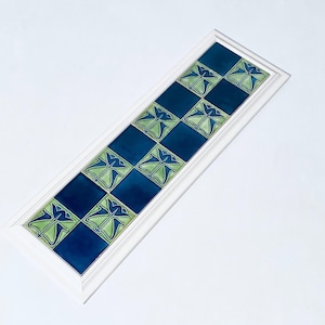 Könnte beinhalten: Eine gerahmte Fliesenplatte mit einem sich wiederholenden Muster aus grün und blau stilisierten Blumen. Die Fliesen sind in einem Schachbrettmuster angeordnet.