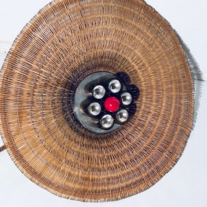 May include: A round, woven wicker lampshade with a metal base and six light bulbs, one of which is red.