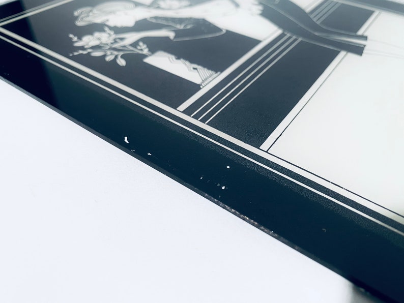 May include: A black and white framed print of a woman in a dress holding a bouquet of flowers. The frame has a silver border.