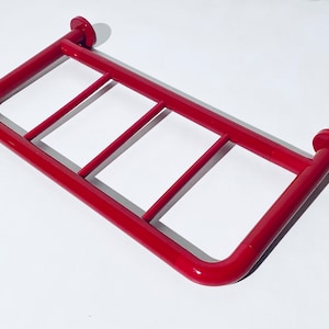 Puede incluir: Barra de agarre de metal roja con tres barras horizontales para apoyo. La barra de agarre está diseñada para la seguridad del baño.