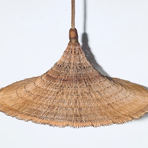 May include: A large, wide-brimmed, conical straw hat with a woven design. The hat is hanging from a cord.