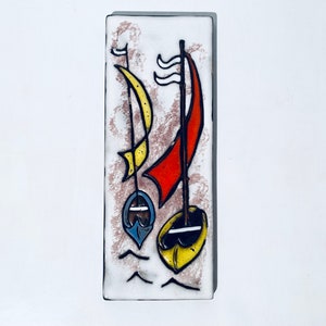 Può includere: Una piastrella da parete in ceramica con sfondo bianco e un'immagine stilizzata di due barche a vela con vele rosse, gialle e blu. Le barche a vela sono su uno sfondo bianco con un bordo marrone testurizzato.