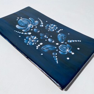 Könnte beinhalten: Eine rechteckige blaue Keramik-Servierplatte mit einem weißen Blumenmuster. Die Platte hat eine glänzende Oberfläche und ist mit weißen Blumen und Blättern verziert.