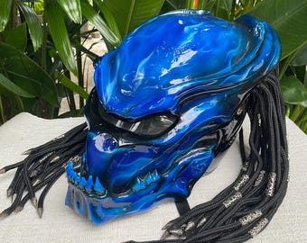 May include: Blue and black Predator-style motorcycle helmet with dreadlocks. The helmet has a blue and black paint job with a flame design. The dreadlocks are black and have silver beads.