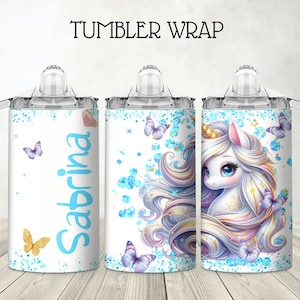 May include: A white tumbler wrap with a unicorn design. The unicorn has a rainbow mane and tail, and blue eyes. The background is a light blue with white glitter and butterflies. The tumbler has a clear lid and handle. The name Sabrina is written on the tumbler.