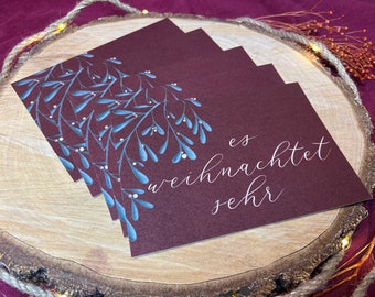 May include: Four burgundy cards with a blue and white mistletoe design. The top card has the text "es weihnachtet sehr" in white.