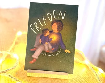 May include: A green card with the word "FRIEDEN" in white lettering. An illustration of an adult and a child holding a glowing light. The text "mit mir selbst" is written below the illustration.