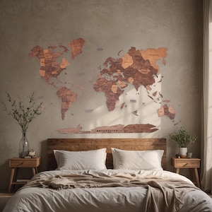 May include: A wooden world map with a light brown finish is mounted on a wall above a bed with white bedding and a brown throw blanket. The map is made up of individual pieces of wood that fit together to form the continents. The map includes the text "ANTARCTICA".