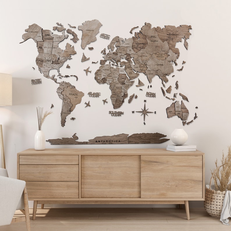 May include: A detailed wooden world map, with country outlines and names, in shades of brown. Decorative elements include airplanes, boats, and a compass rose. The map is mounted on a white wall above a wooden cabinet, adding a touch of global style.