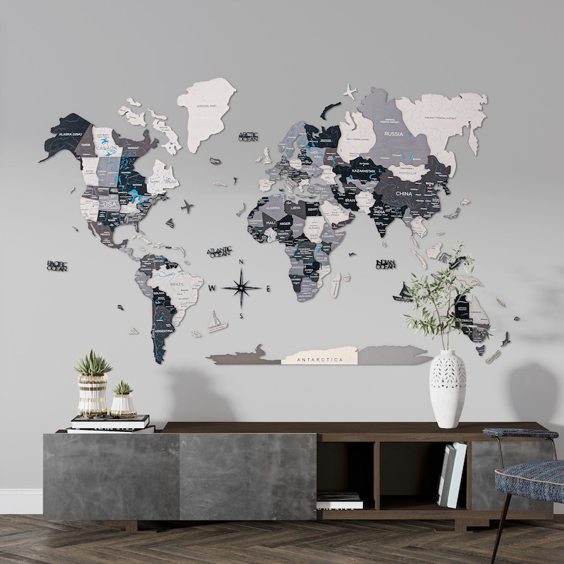 May include: A large, 3D wooden world map in grey, black, and white, fixed to a grey wall. The map features country names and ocean labels. A compass rose and decorative elements are also included.